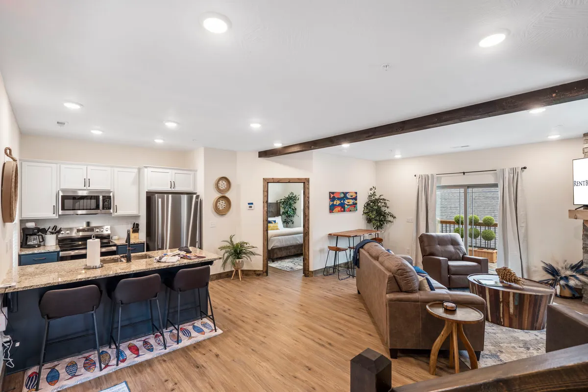 An open-concept interior showcasing a kitchen island seamlessly connected to a living room with inviting seating. Natural light filters in through the windows, creating a bright, communal atmosphere perfect for cooking, dining, and entertaining.
