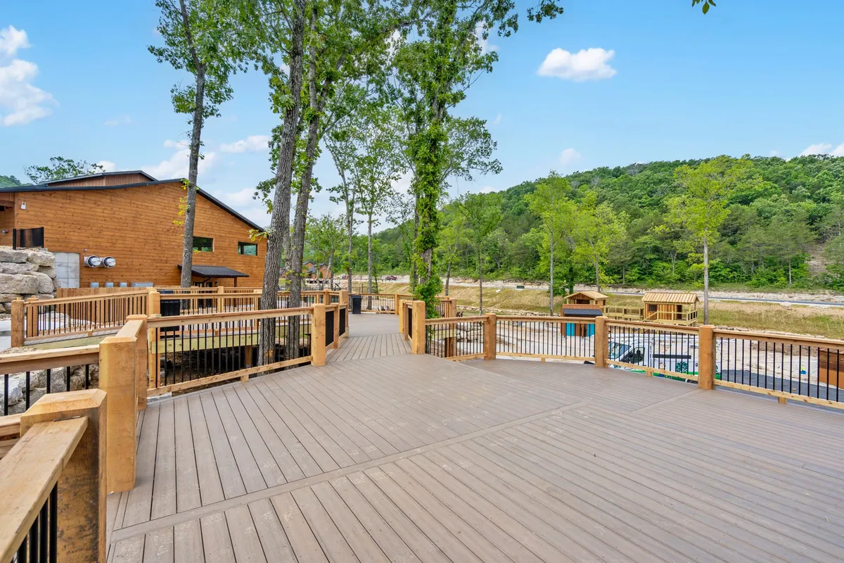 A spacious wooden deck overlooking surrounding trees and distant hills, offering an inviting spot for outdoor meals, sunset drinks, or casual gatherings.