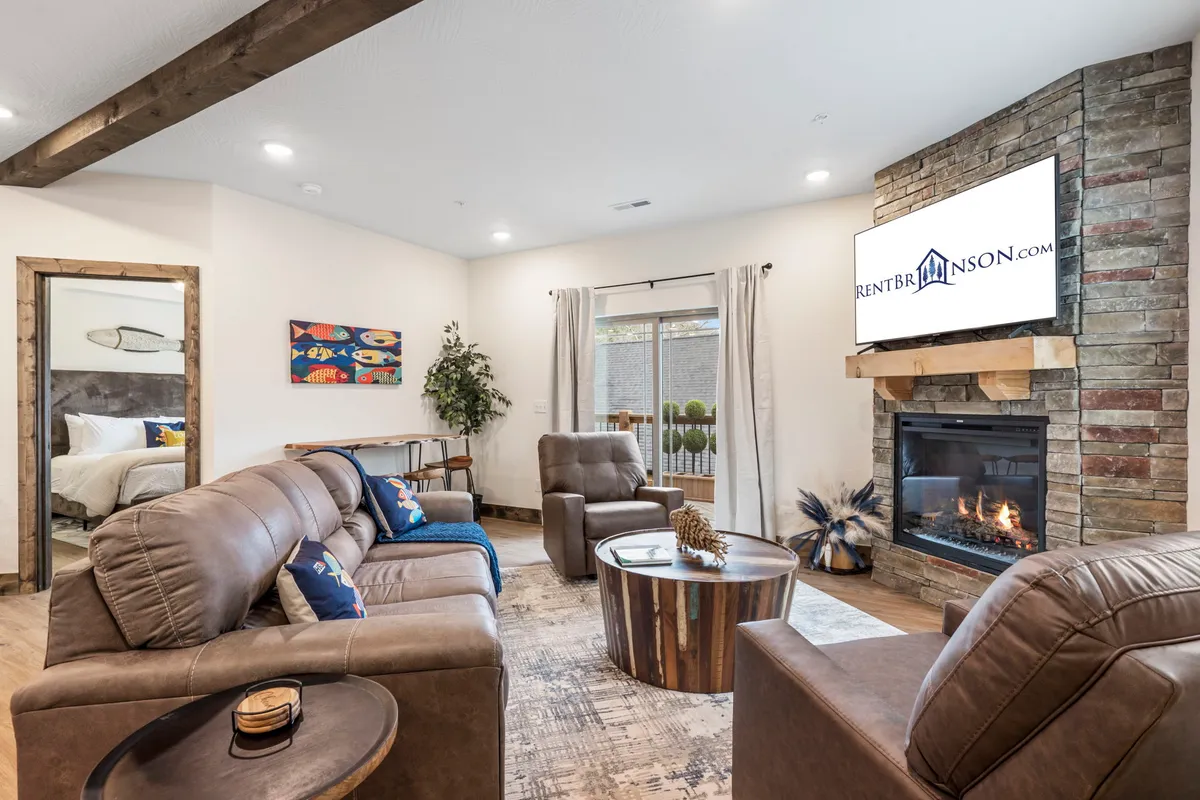 The image showcases a cozy living area with a glowing fireplace as the centerpiece, surrounded by comfortable seating, stylish decorative artwork, and lush indoor plants, all bathed in natural light. The scene evokes warmth and comfort, inviting guests to unwind and spend quality time together.